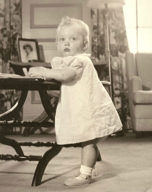 Image: Black and white photo of toddler Temple Grandin in white dress and fancy shoes.