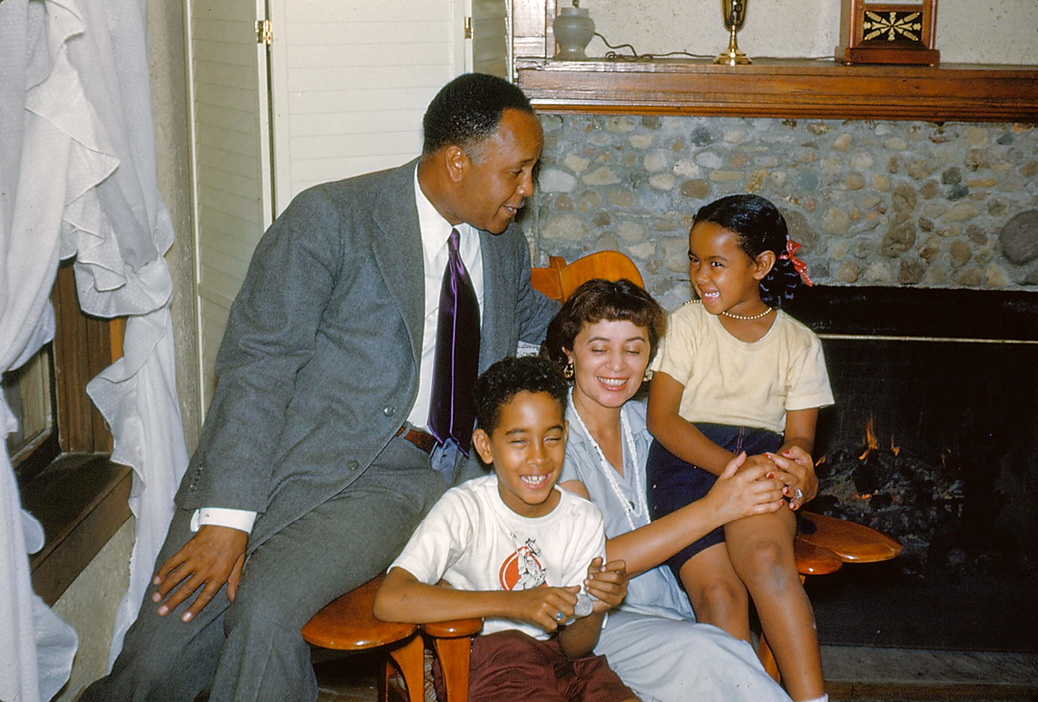 Percy Julian sits on the arm of a chair in which his wife and son are seated. His daughter sits on the opposite arm.