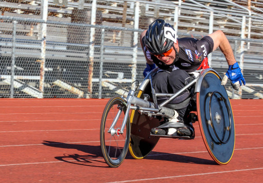Rory Cooper in leaned back in a racing chair on a red track, leaned down to become aerodynamic, pushing himself to win