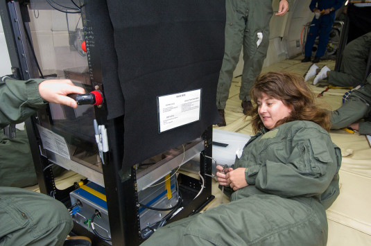 杰基·奎因（Jackie Quinn）检查地面上的一件设备，四名团队成员在后台工作