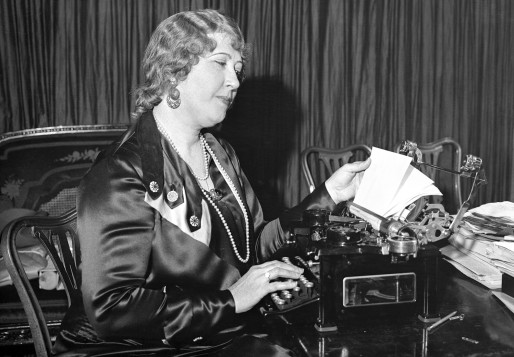 一位穿着丝绸衣服的中年妇女坐在椅子上检查打字机