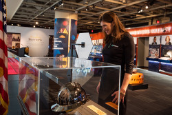 Women examines a hardhat inside a glass display