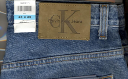 牛仔腰带背面的皮革补丁的特写照片。贴片为棕褐色，印有Calvin Klein商标。