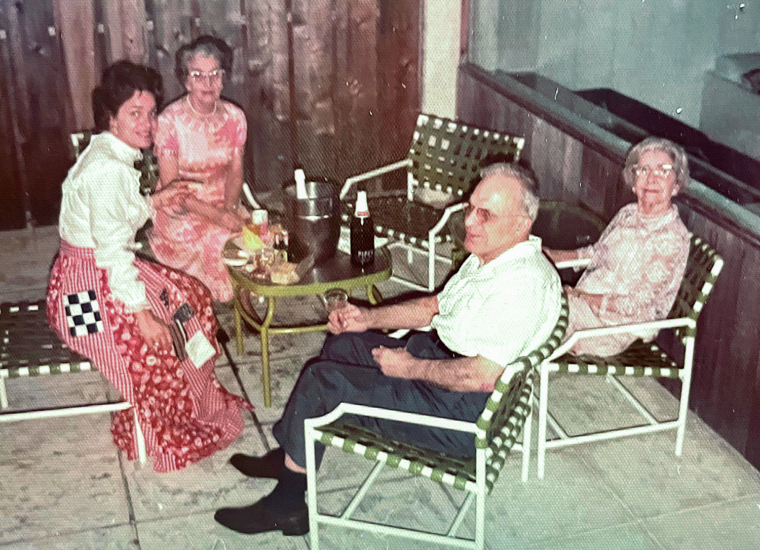 Family consisting of three women and one man all sitting in chairs facing each other. 