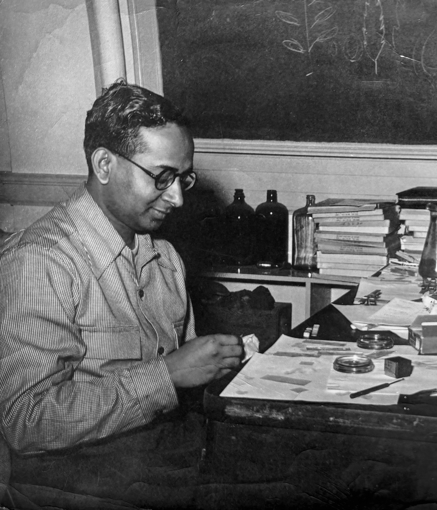 Man wearing colored shirt sitting in front of lab table with implements