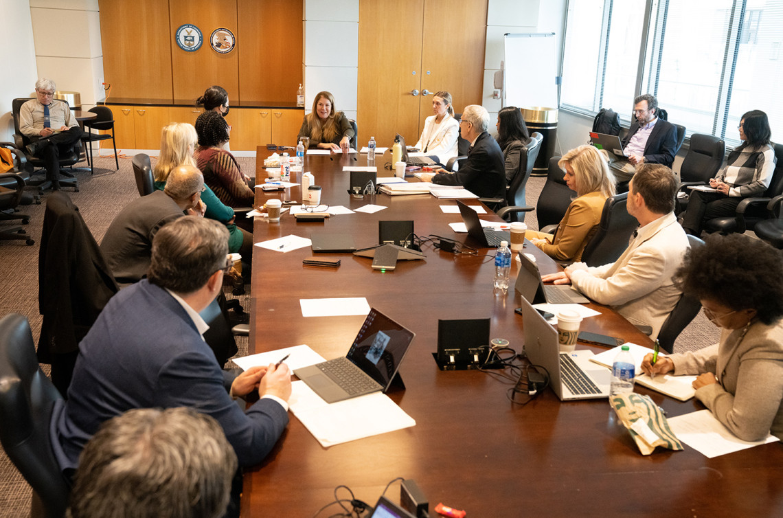 Kathi Vidal sits at the head of a conference table meeting with members of the Patent Public Advisory Committee