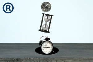 A quarter, hourglass, and an analog alarm clock are falling through a hole in the middle of a wooden desk. The registered trademark sign, a capital R in a circle, appears in the left-hand corner. 